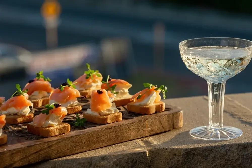 Kleine knusprige, gebackene Brotstücke mit Lachs und Kaviar, Champagne in Kelchglas